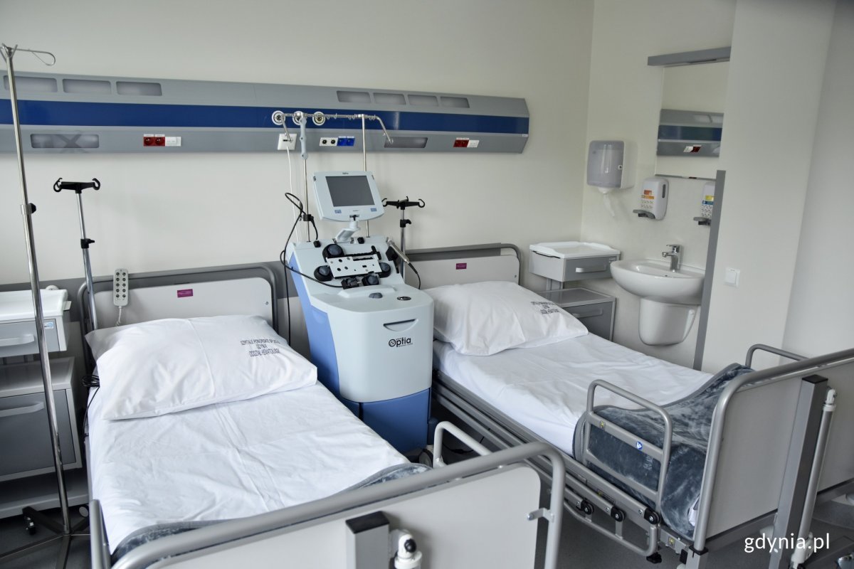 Pokój w szpitalu, z dwoma łóżkami szpitalnym i aparaturą.