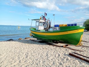 Kuter rybacki stojący na plaży, w tle morze i pogodne niebo