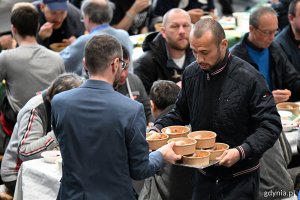 Radny Marcus da Silva niesie gościom tacę z posiłkami 