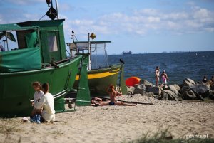 Plaża w Orłowie. Przy dwóch kutrach rybackich opala się grupa osób, w tle morze. Fot, Przemysław Kozłowski