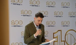 Przy mikrofonie prowadzący wydarzenie aktor Krzysztof Berendt