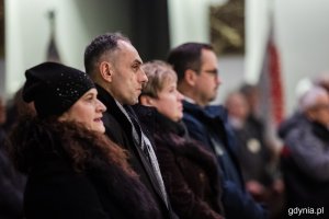 Grupa osób w kurtkach stojących w kościele