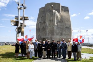 Ludzie stoja pod pomnikiem pozując do fotografii.
