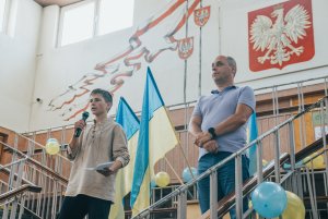 Chłopiec z miktofonem na tle flag