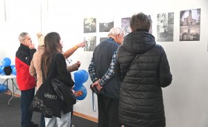 Grupa ludzi ogląda fotografie na ścianie