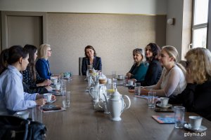 Kilka kobiet siedzi za stołem w gabinecie i rozmawiają.