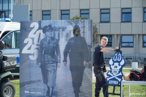 Monidło i obok stojący policjant 