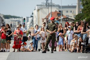 Mieszkańcy miasta na pierwszym planie żołnierz w mundurze