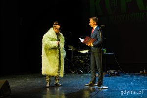 Mężczyzna w garniturze i mężczyzna w korzuchu na scenie 