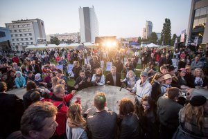 Goście festiwalu NNW 2023 wypowiadający się podczas panelu. Znajdują się na placu Grunwaldzkim w Gdyni, w tle - tłum ludzi i wysokie budynki. 