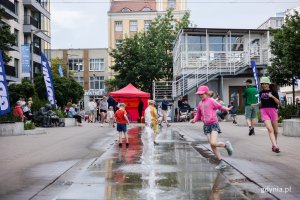 Dzieci biegają przy fontannie.