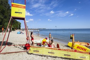 Grupa ratowników na plaży obok wieżyczki.