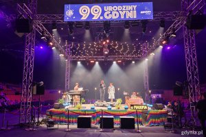 Hala Polsat Plus Arena Gdynia, scena, kolorowe oświetlenie, na scenie stoją wicewojewoda i prezydent Gdyni, napis "99. urodziny Gdyni" na wyświetlaczu