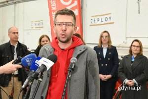 Mężczyzna mówiący do kilku ustawionych obok siebie mikrofonów