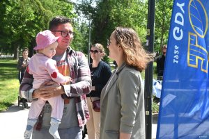Mężczyzna z dziewczynką w r&oacute;żowym dresie na rękach, obok kobieta