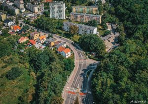 widok z góry na ulicę, w tle ruch uliczny, budynki i zieleń, widok z góry na miasto