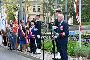 Waldemar Świto - prezes gdyńskiego koła Związku Sybiraków podczas uroczystości na węźle Zesłańców Sybiru. Za nim posterunek honorowy przy tablicy z nazwą weżła oraz poczty sztandarowe biorące udział w yuroczystości // fot. Magdalena Czernek