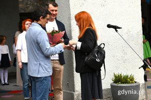 Mężczyzna wręcza kwiaty kobiecie z rudymi włosami
