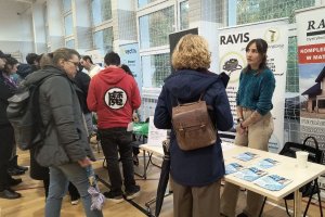 Stoiska pracodawc&oacute;w na sali gimnastycznej oraz mieszkańcy rozmawiający z przedstawicielami firm.