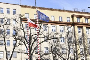 Podniesione flagi Polski i NATO na tle budynku Dowództwa Marynarki Wojennej w Gdyni.