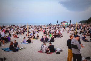 Tłum ludzi na plaży słucha koncertu.