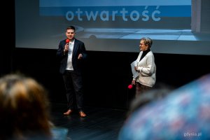 Wiceprezydent Gdyni Maciej Zielonka przemawia do mikrofonu w Gdyńskim Centrum Filmowym, w tle hasło festiwalu: otwartość