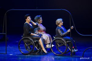Trzy kobiety na wózkach inwalidzkich na scenie.