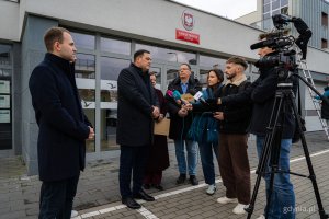 Od lewej: radny Norbert Anisowicz, sekretarz miasta Łukasz Kobus, prezydent Gdyni Aleksandra Kosiorek, rzecznik prasowy Urzędu Miasta Gdyni Tomasz Złotoś i przedstawiciele mediów przed nowo otwartym Punktem Obsługi Mieszkańców Urzędu Miasta Gdyni na Chwarznie-Wiczlinie, w lokalu przy ul. Tęczowej 37 (fot. Kamil Złoch)