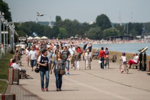 Ludzie idący po bulwarze, w tle plaża i morze.