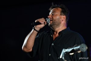 Aktor Teatru Muzycznego Rafał Ostrowski z mikrofonem w czasie występu, fot. Michał Puszczewicz