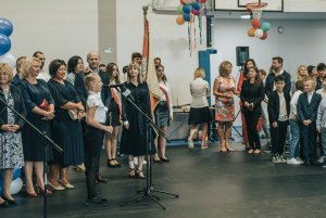 Młoda dziewczyna przy mikrofonie w tle przedstawiciele władz