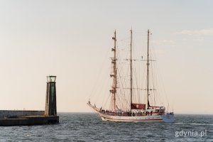 Nabrzeże i latarnia morska, w tle żaglowiec płynący po morzu