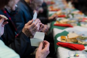 Goście wigilii dla samotnych i potrzebujących dzielący się opłatkiem