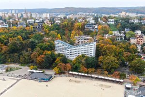 Widok z lotu ptaka na hotel "Błękitny żagiel" przy plaży Śródmieście, który otaczają drzewa w jesiennej szacie. W tle okoliczne budynki // fot. Michał Puszczewicz