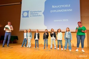 Osoby na scenie pozujące do zdjęcia po wręczeniu nominacji