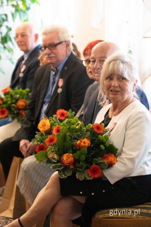 Seniorzy z bukietami w pomarańczowej tonacji