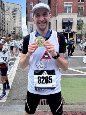 Mężczyzna w czarno-białym stroju sportowym pozujący z zawieszonym na szyi medalem