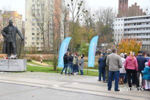 Grupa ludzi stojąca w kolejce na placu przed pomnikiem Józefa Piłsudskiego