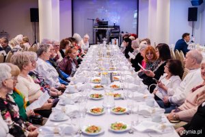 Grupa senior&oacute;w siedzi przy elegancko zastawionym stole