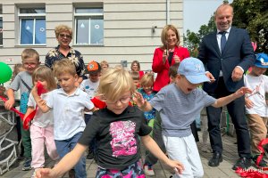 Dzieci zbiegające po schodach w tle dorośli klaszczący w dłonie