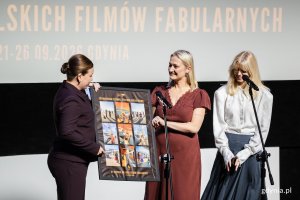 Agata Kozierańska-Burda &ndash; dyrektor Festiwalu Polskich Film&oacute;w Fabularnych i Joanna Łapińska &ndash; dyrektor artystyczna Festiwalu Polskich Film&oacute;w Fabularnych wręczające grafikę festiwalową wiceprezydentce Gdyni Oktawii Gorzeńskiej podczas gali otwarcia 51. Festiwalu Polskich Film&oacute;w Fabularnych