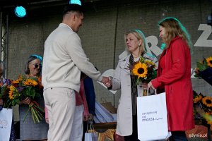 Beata Zastawna &ndash; przewodnicząca Rady Miasta Gdyni i Hanna Niedźwiecka-Pasternak &ndash; zastępca naczelnika Wydziału Ogrodnika Miasta wręczają nagrodę jednemu z uczestnik&oacute;w konkursu &bdquo;Gdynia w kwiatach&rdquo; 
