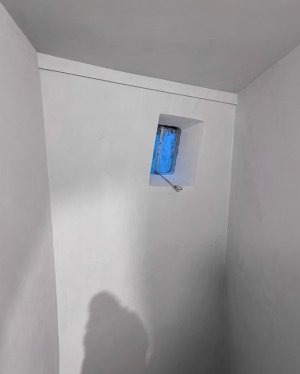 Ściana z małym okienkiem na klatce schodowej.