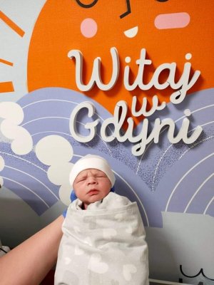 Szymon – pierwszy gdynianin urodzony w 2022 roku - na tle ściany z napisem: "Witaj w Gdyni" // fot. Szpitale Pomorskie