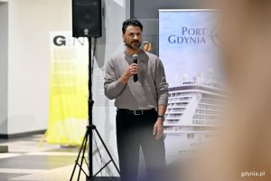 Kurator wystawy &bdquo;Gen 100 &ndash; gdyński kod wsp&oacute;lnoty&rdquo; Maksymilian Bochenek przemawiający podczas wernisażu
