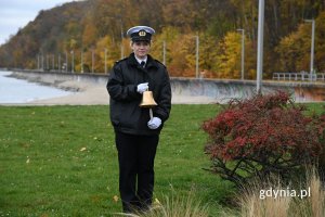 Kobieta w mundurze stojąca na trawie i trzymająca dzwon