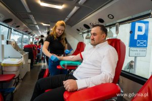 Mężczyżczyzna w białej koszuli oddaje krew 