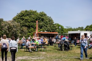 Ludzie siedzący przy stolikach przy food truckach z jedzeniem