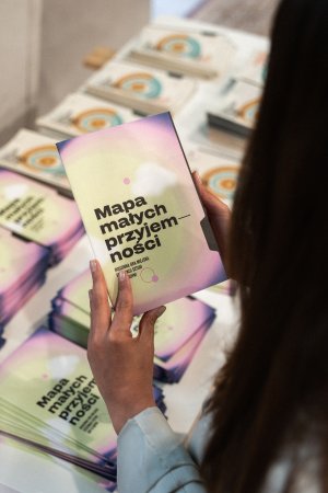 Ktoś trzyma w rękach broszurę z napisem: Mapa małych przyjemności