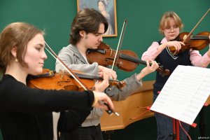 Troje uczni&oacute;w gra na skrzypcach